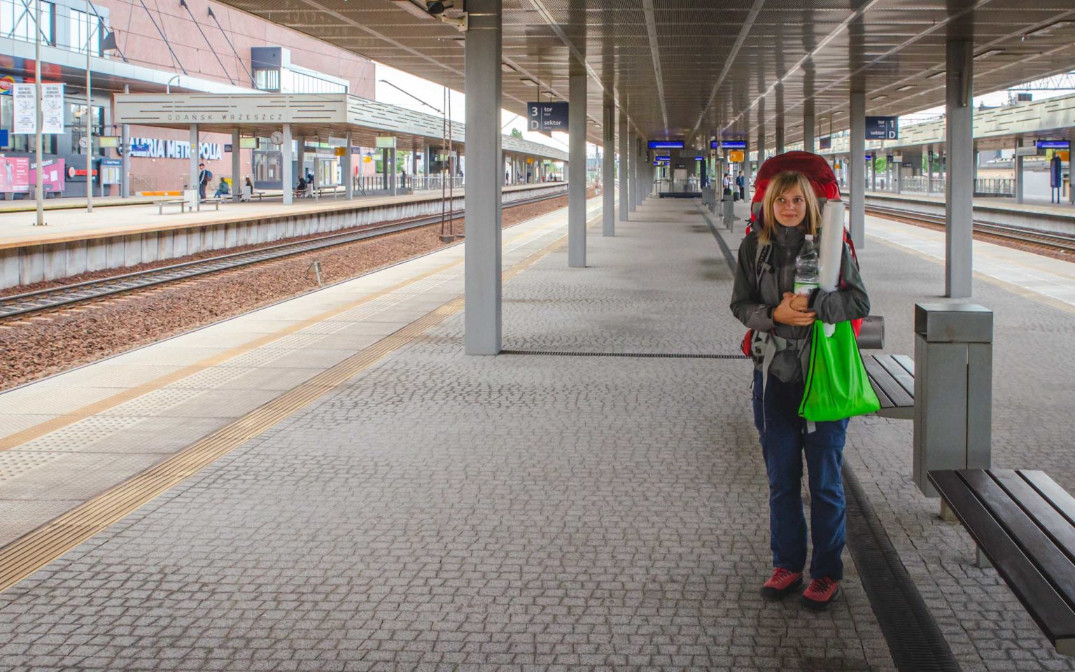 Kobieta z plecakiem stoi na dworcu kolejowym przed podróżą na Lofoty
