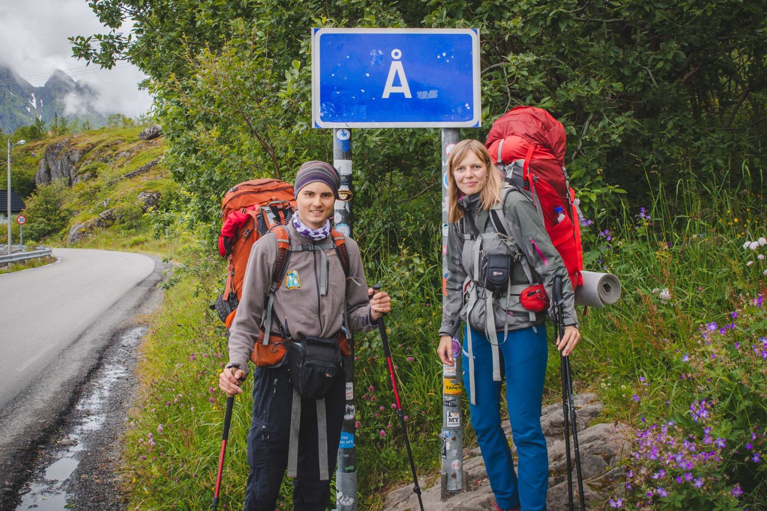 Mężczyzna i kobieta stoją przy znaku drogowym Å