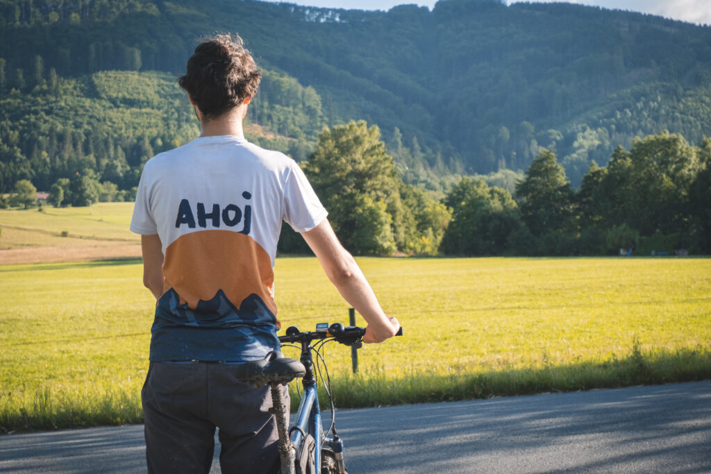 Błażej w koszulce z napisem "Ahoj" trzymający rower