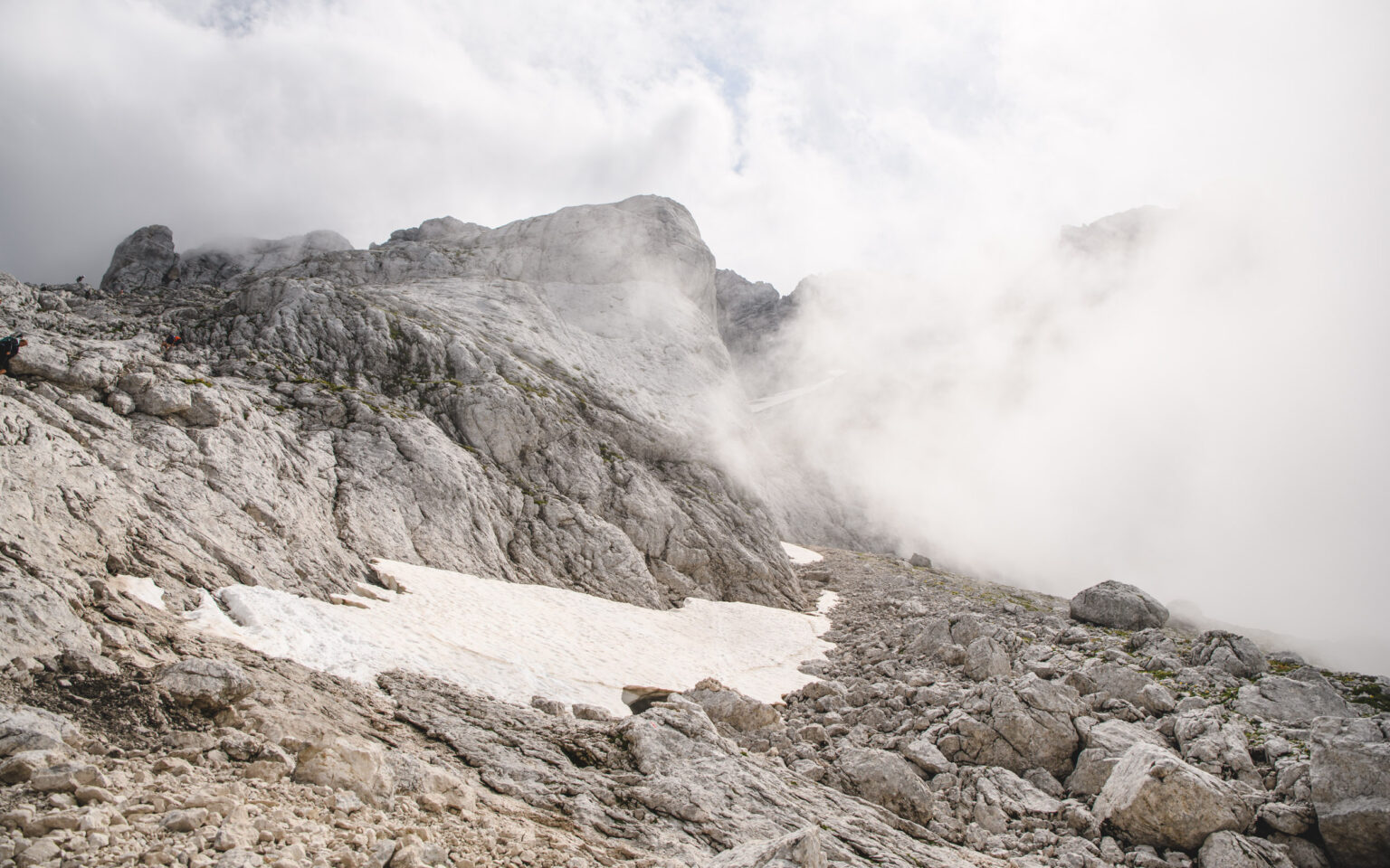 Alpy Julijskie we mgle, na skałach płat śniegu